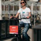 Model trägt Fisch Illustration T-Shirt aus Bio Baumwolle und fährt Rad